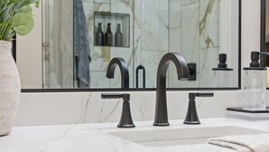 A bathroom with a marble sink, a large mirror, and a shower with a glass enclosure.