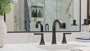 A bathroom with a marble sink, a large mirror, and a shower with a glass enclosure.
