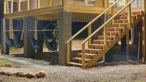 Eine Holzterrasse mit Treppe, die zu einer zweiten Ebene führt, gestützt von Betonstützen.