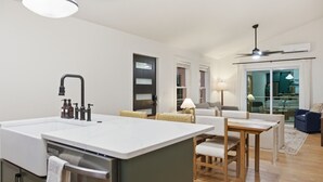 Eine moderne Küche mit einer großen Kochinsel, integrierten Geräten und einem Essbereich mit Tisch und Stühlen.