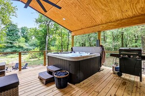 Eine Holzterrasse mit Whirlpool, Grill und Gartenmöbeln.