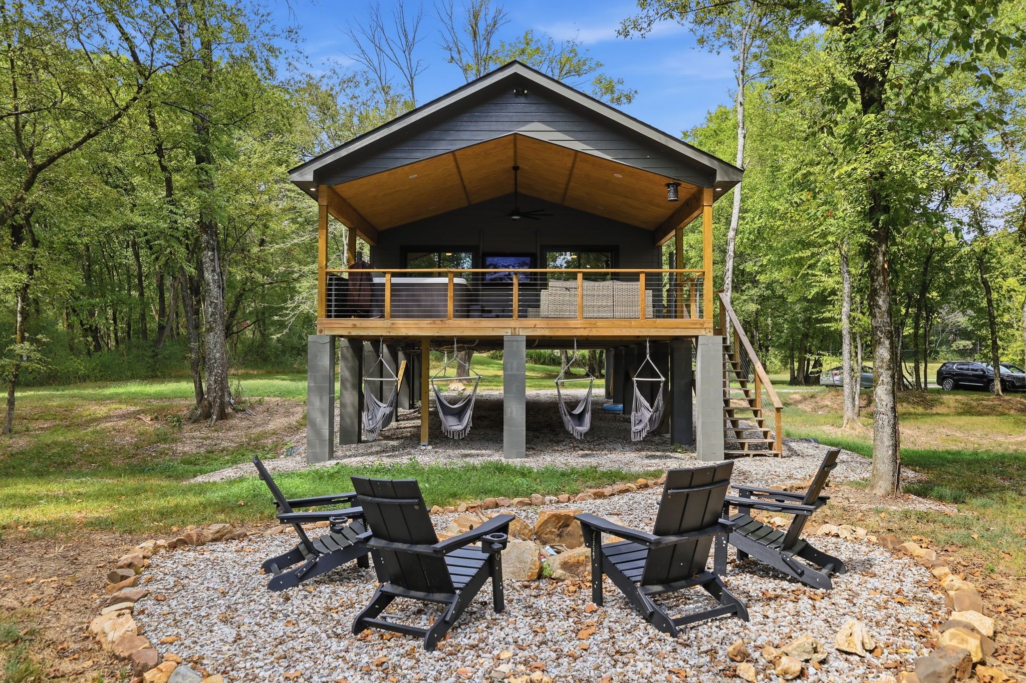 Una cabaña con balcón, mobiliario exterior y vistas del bosque circundante.