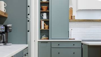 A modern kitchen with grey cabinets, wooden countertops, and a built-in coffee machine.