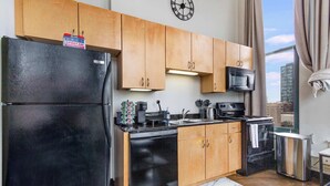 A modern kitchen with wooden cabinets, a black refrigerator, a microwave, and a dishwasher. - Modern West Loop Gem-City Views & Prime Location 1 (Chicago)