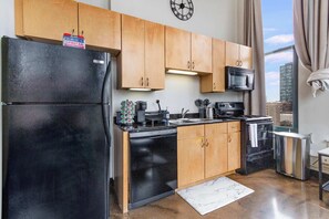 A modern kitchen with wooden cabinets, a black refrigerator, a microwave, and a dishwasher. - Modern West Loop Gem-City Views & Prime Location 1 (Chicago)