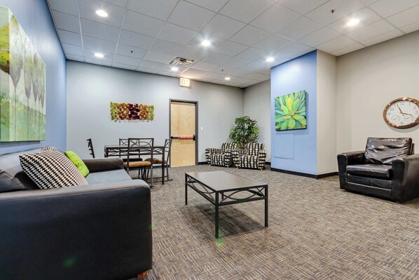 A waiting area with a sofa, chairs, a coffee table, and a clock on the wall.