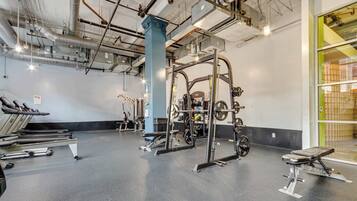 Et fitnesscenter med løbebånd, styrkemaskiner og en squat-stang.