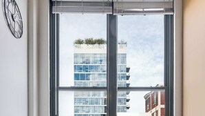 A modern office space with a large window, a clock on the wall, and a table with chairs. - Modern West Loop Gem-City Views & Prime Location 2 (Chicago)
