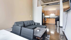 A modern living space with a sectional sofa, a small table, and a kitchenette in the background. - Modern West Loop Gem-City Views & Prime Location 2 (Chicago)
