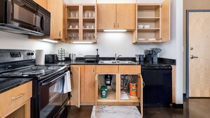 A kitchen with wooden cabinets, a black stove, a sink, and a dishwasher. - Modern West Loop Gem-City Views & Prime Location 2 (Chicago)
