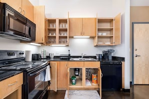 A kitchen with wooden cabinets, a black stove, a sink, and a dishwasher.
