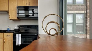 Una cucina con mobili in legno, un forno a microonde nero, un forno nero e un oggetto a spirale dorato sul bancone.