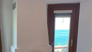 Ein Zimmer mit Kamin, einem Fenster mit Meerblick und einem Holzgestell.