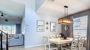 A dining area with a wooden table and white chairs, a ceiling fan, and a dining table with a bowl of pinecones. - My Disney Retreat | Free Resort Access-Disney 9min (Four Corners)