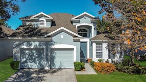 A two-story house with a garage, a small attached garage, and a front yard with a tree and shrubs. - My Disney Retreat | Free Resort Access-Disney 9min (Four Corners)
