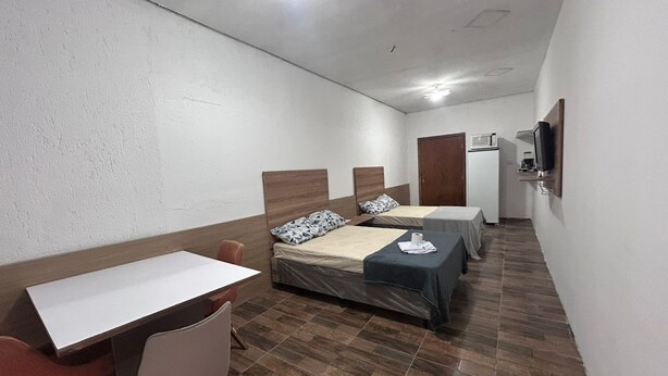 A hotel room with two beds, a desk, a chair, and a television. - Studio zona norte São Paulo Tucuruvi (São Paulo)