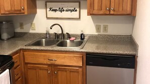 Eine Küche mit Holzausstattung, einer Edelstahlspüle und einem Geschirrspüler.