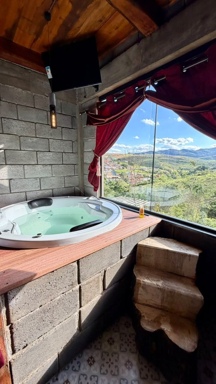 A hot tub in a room with a view, a brick wall, and a wooden ceiling.