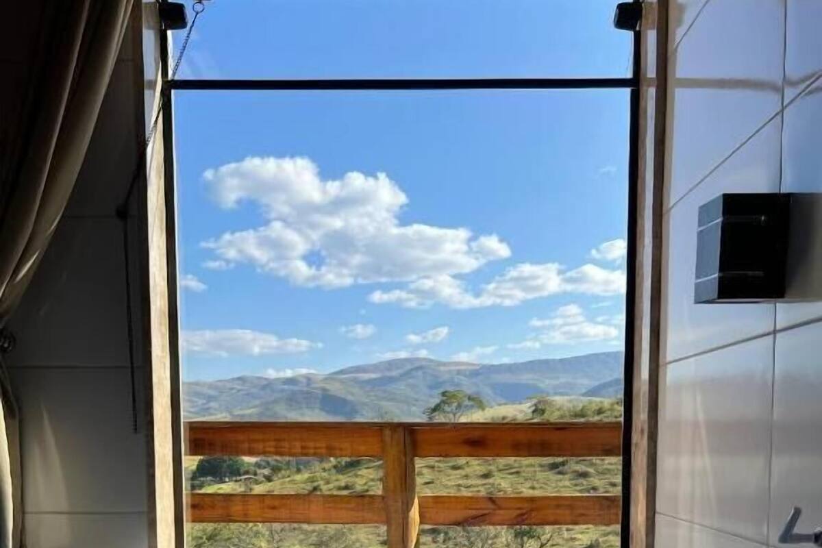 A bathroom with a large window, a wooden fence outside, and a bathtub.