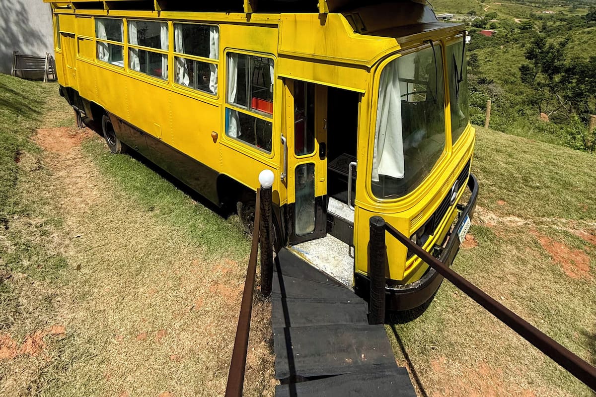 A yellow train car parked on a grassy area with a scenic view of mountains in the background.