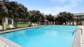 A swimming pool with lounge chairs and a fence. - Iberia House & Suites (New Iberia)