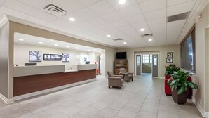 A reception area with a counter, seating, and a TV. - Iberia House & Suites (New Iberia)
