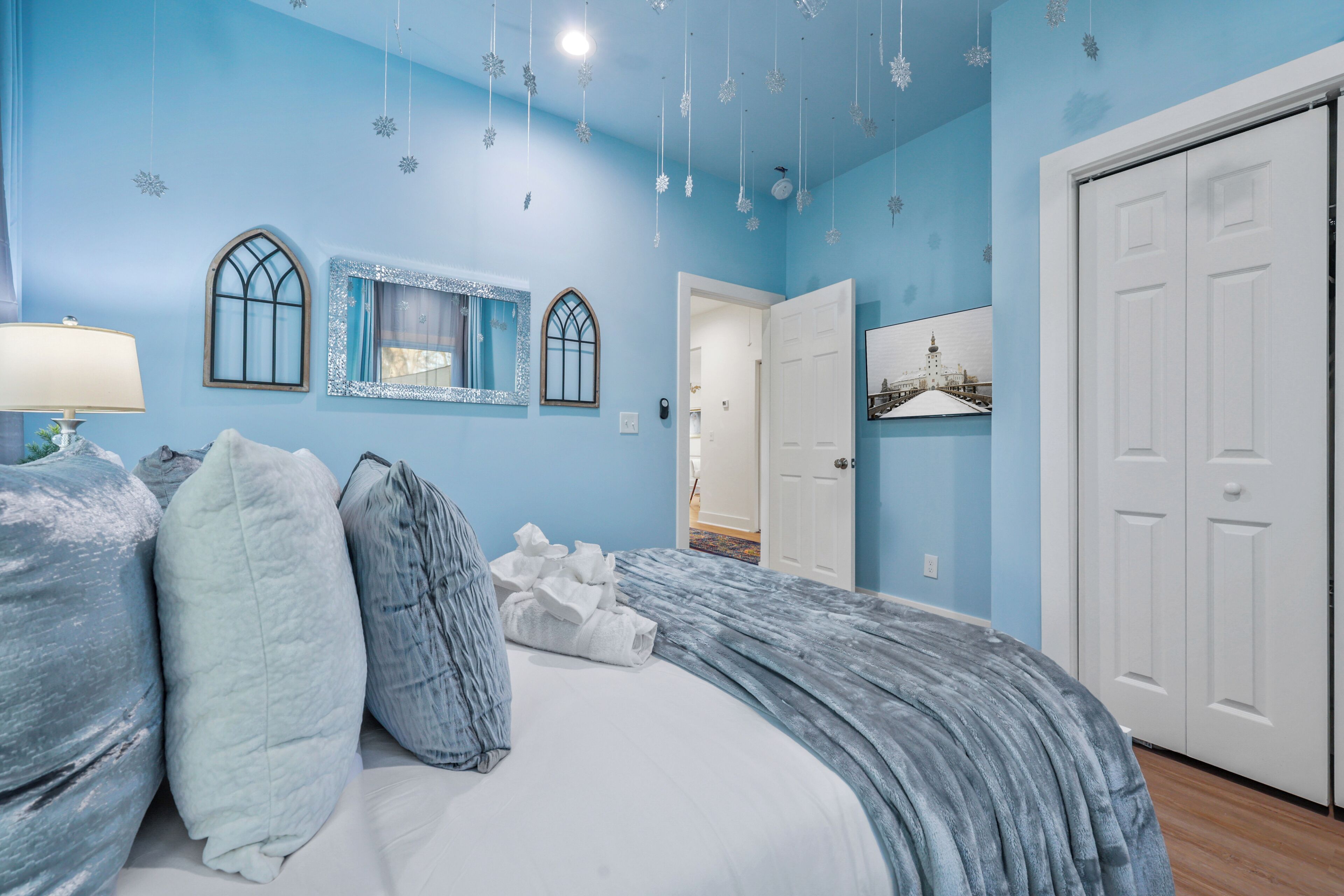 Ein Schlafzimmer mit Bett, Kissen, Nachttisch, Spiegel und Tür.