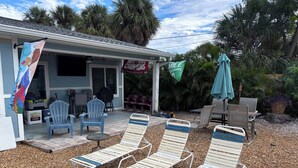 A patio area with lounge chairs, a table, and a covered seating area. - The Love Shack is a remodeled and roomy 2 BR house in fabulous St. Pete Beach (St. Pete Beach)