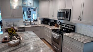 A modern kitchen with white cabinets, a stainless steel microwave, a stove, and a marble countertop. - The Love Shack is a remodeled and roomy 2 BR house in fabulous St. Pete Beach (St. Pete Beach)