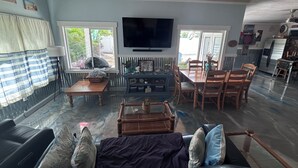 A living room with a sofa, TV, dining table, and chairs. - The Love Shack is a remodeled and roomy 2 BR house in fabulous St. Pete Beach (St. Pete Beach)