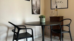 A dining area with a round table, two black chairs, a small potted plant, and a framed picture on the wall. - Apartment i13-C Via Pusterla, 8 - Magenta MI - Rho Fiera-Milano-Aeroporto MPX (Magenta)