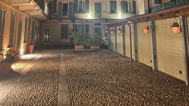 A courtyard with cobblestone flooring, potted plants, and buildings with balconies and windows. - Apartment i13-C Via Pusterla, 8 - Magenta MI - Rho Fiera-Milano-Aeroporto MPX (Magenta)