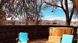 An outdoor patio with two wooden lounge chairs and a wooden hot tub.