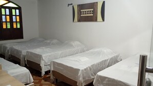 Une chambre avec quatre lits simples, un bureau en bois et une œuvre d’art accrochée au mur.