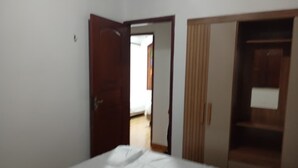 Une chambre à coucher avec un lit, une armoire et une porte ouverte donnant sur une autre pièce.
