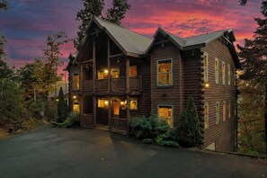 Une grande cabane en rondins dotée de plusieurs balcons et d’une allée menant à l’entrée.