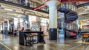 A spacious indoor area with a central spiral staircase, multiple seating areas, and a visible restaurant named 'Hops Chicken'.