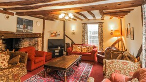 A traditional living room with exposed wooden beams, a fireplace, and a red sofa set. - Chilton Manor House (Sittingbourne)