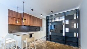A modern kitchen with wooden cabinets, a white countertop, and a built-in black shelving unit. - Ca Moro - Rooms and Apartments (Rimini)