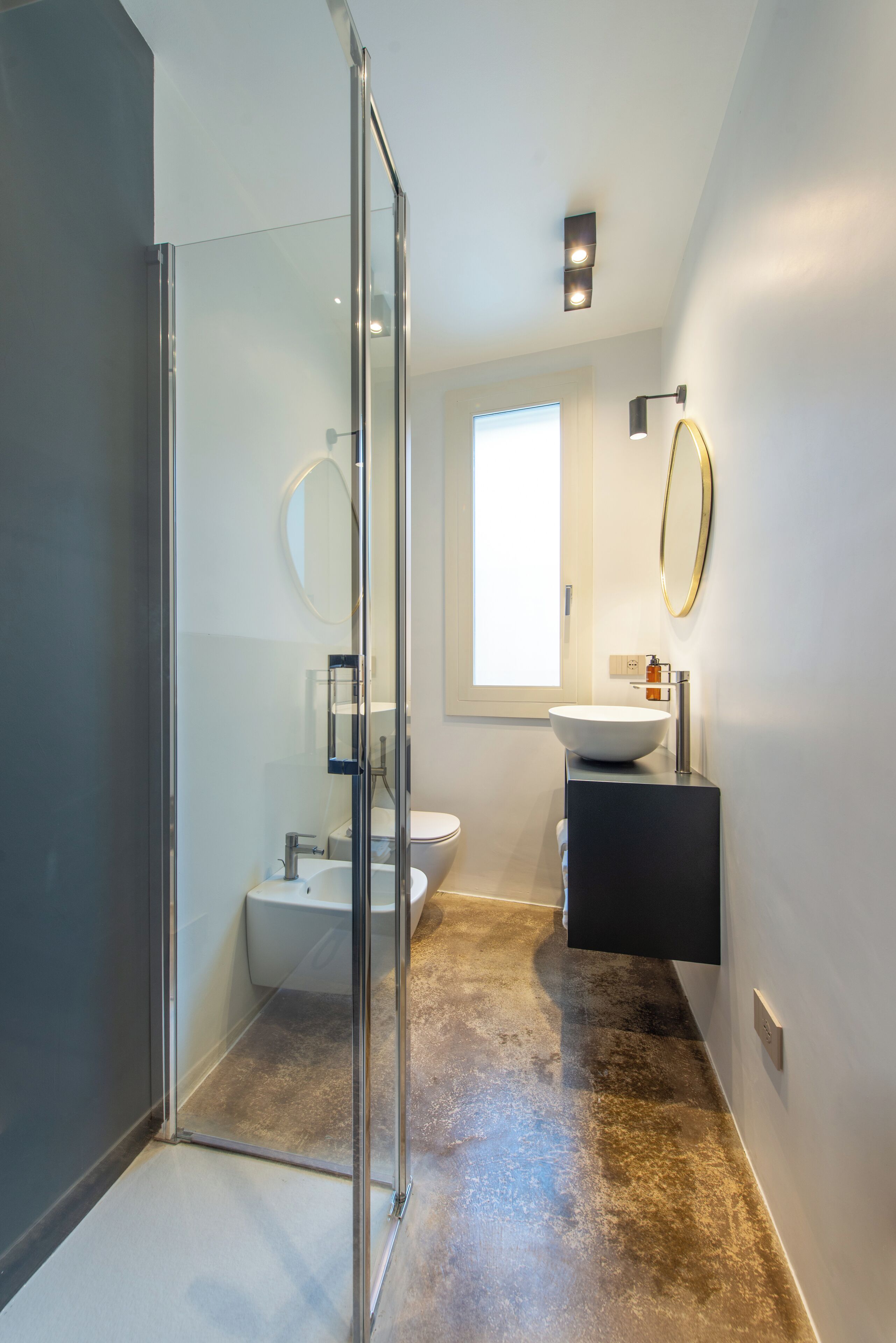 A modern bathroom with a glass shower enclosure, a white sink, and a toilet.
