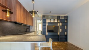 A modern kitchen with a marble countertop, wooden cabinets, and pendant lighting. - Ca Moro - Rooms and Apartments (Rimini)