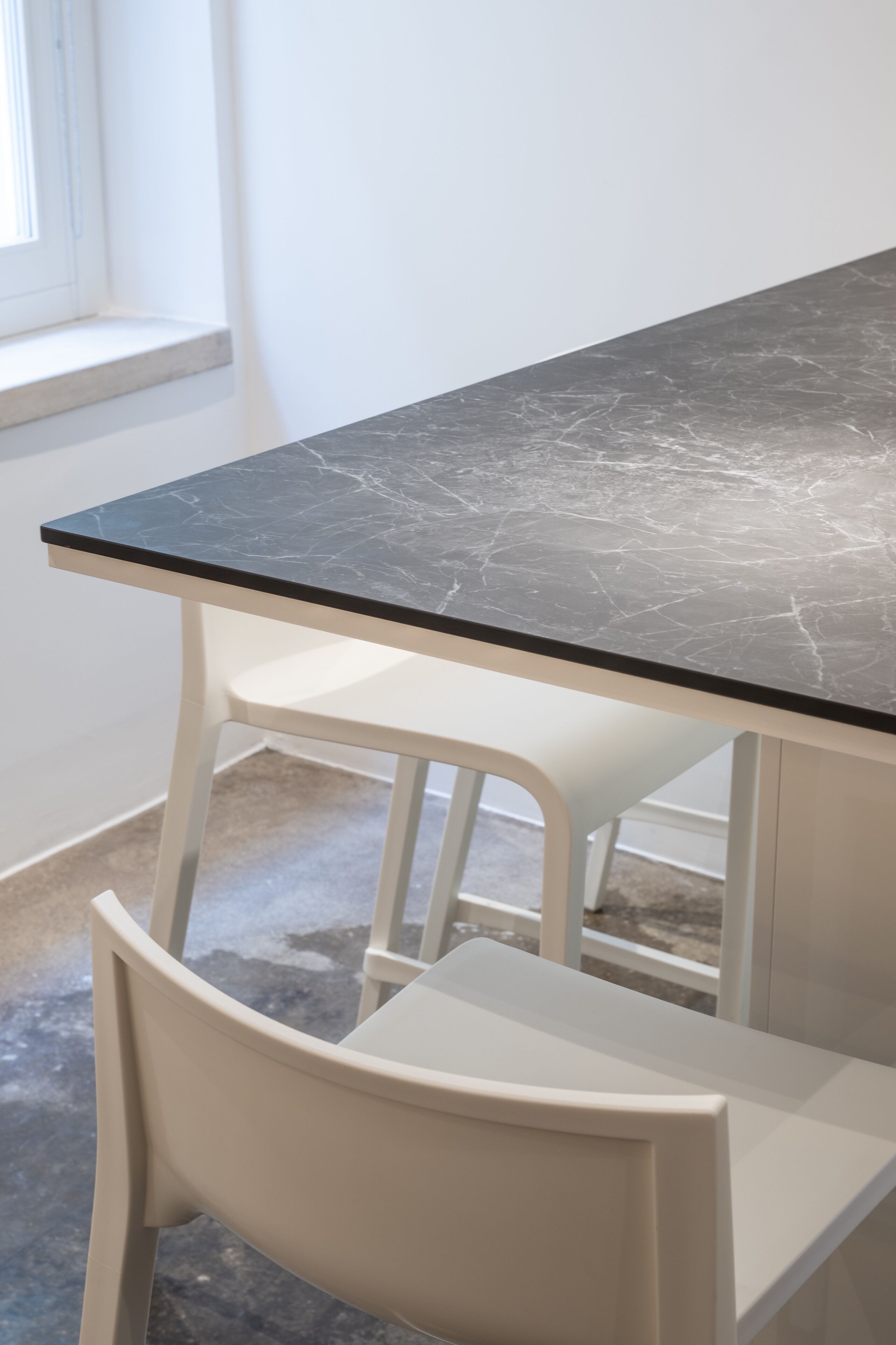 Une table avec un plateau en marbre et des chaises blanches.