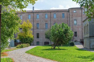 Un edificio in mattoni con numerose finestre e un vialetto lastricato che vi conduce.