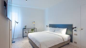 A modern hotel room with a large bed, a desk, and a TV mounted on the wall.