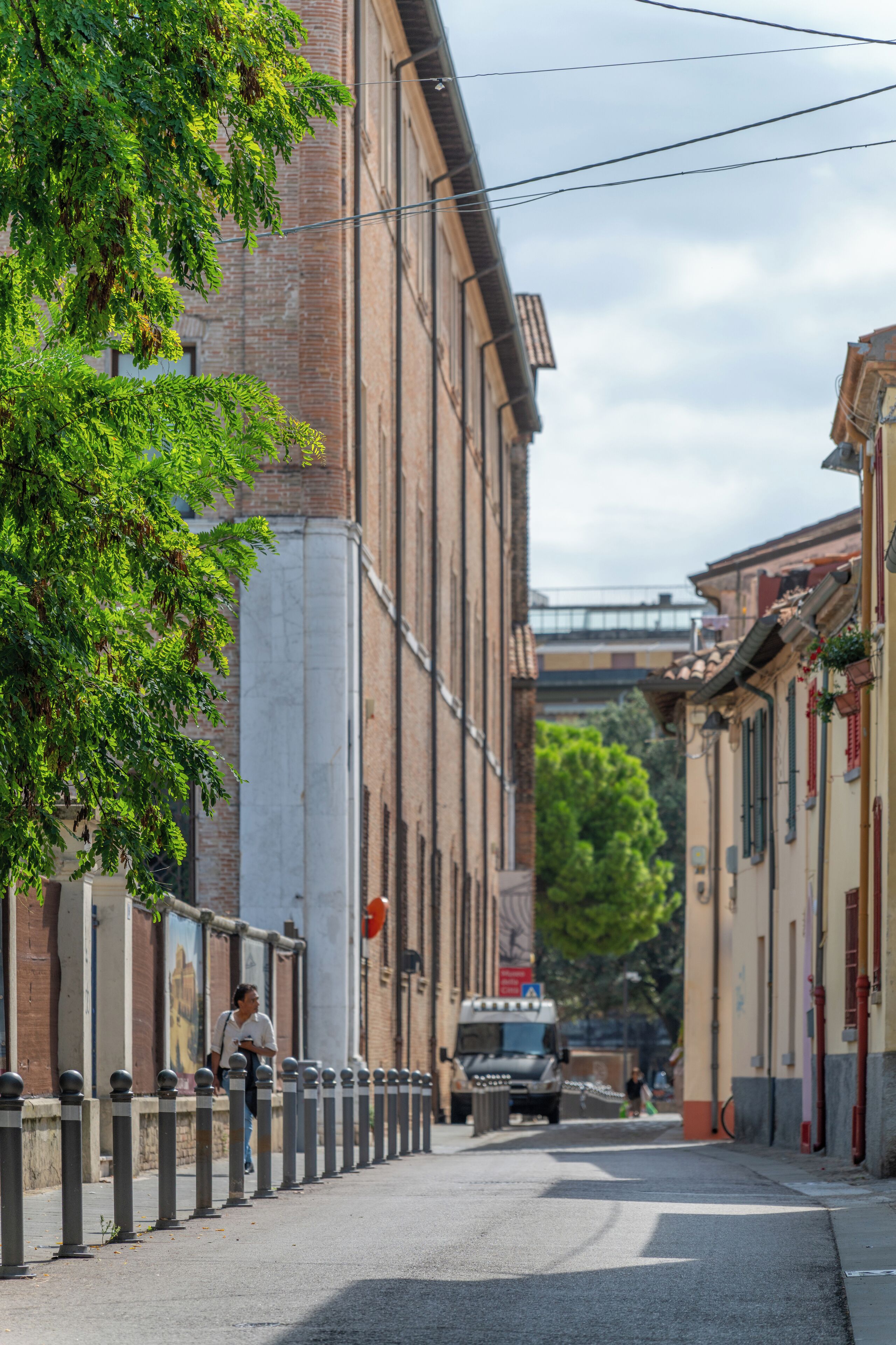 A narrow street lined with traditional buildings, a pedestrian, and a truck.