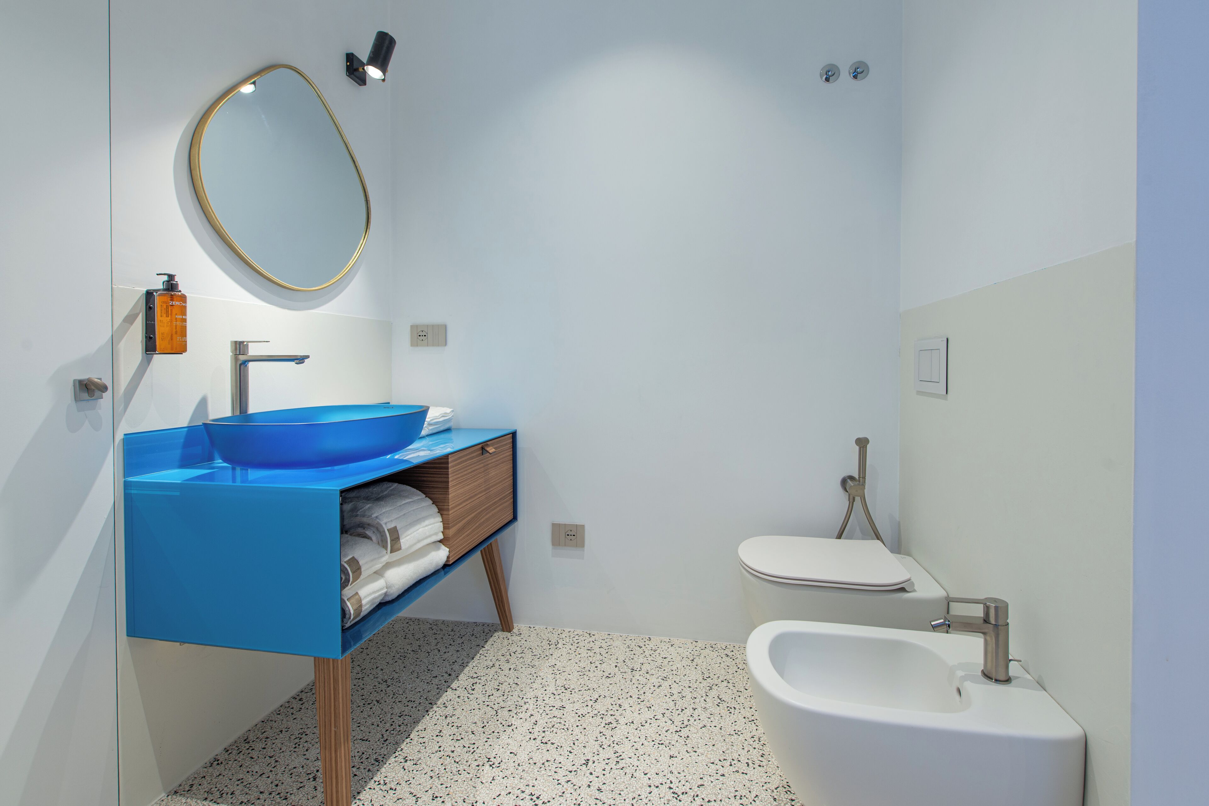 Un bagno moderno con un lavandino blu, un water bianco e un bidet.