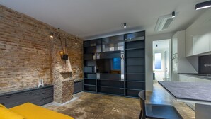 A modern kitchen with a brick wall, black shelving, and a yellow sofa. - Ca Moro - Rooms and Apartments (Rimini)