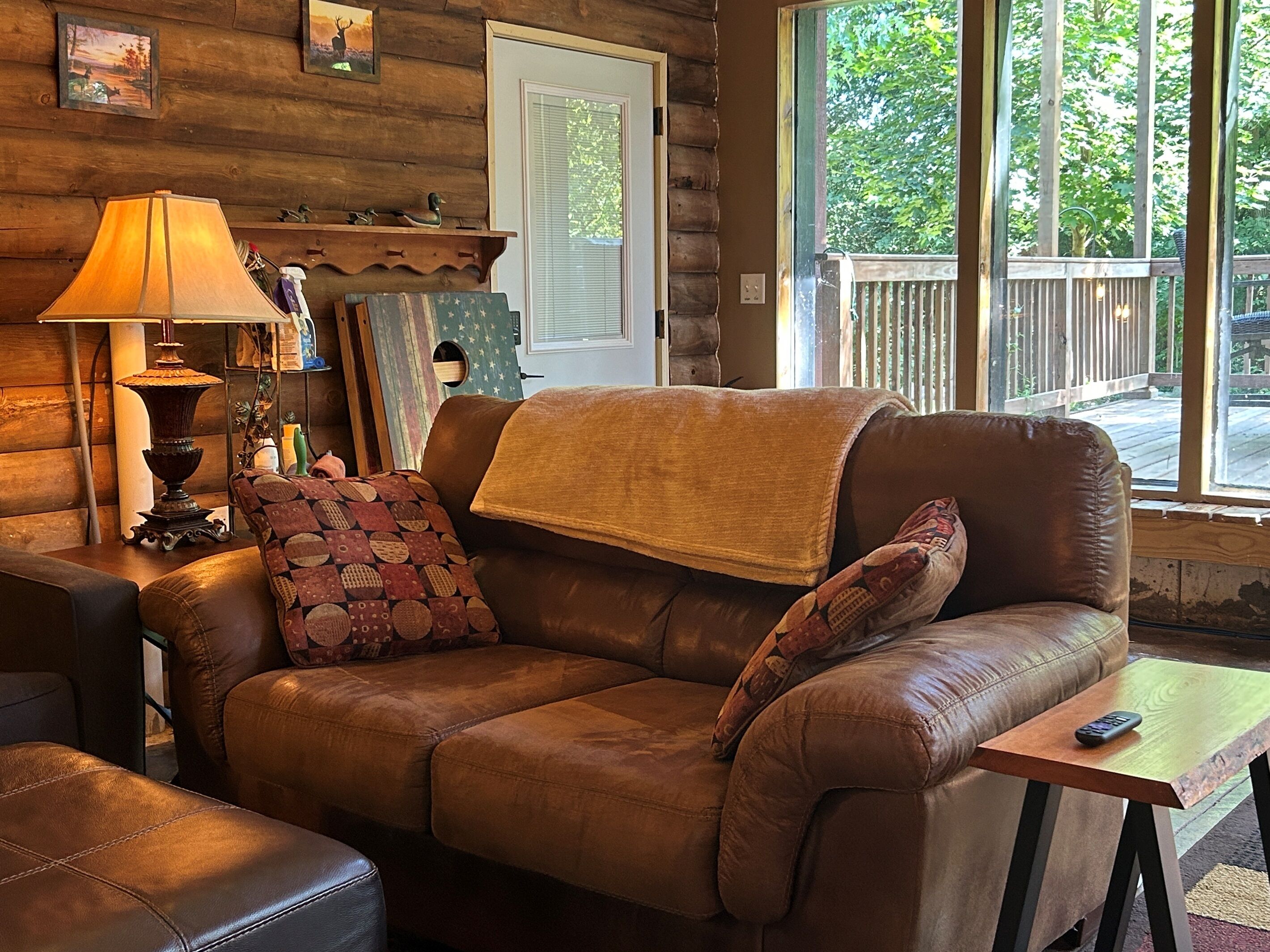 A cozy living room with a leather sofa, a lamp, and a small table.