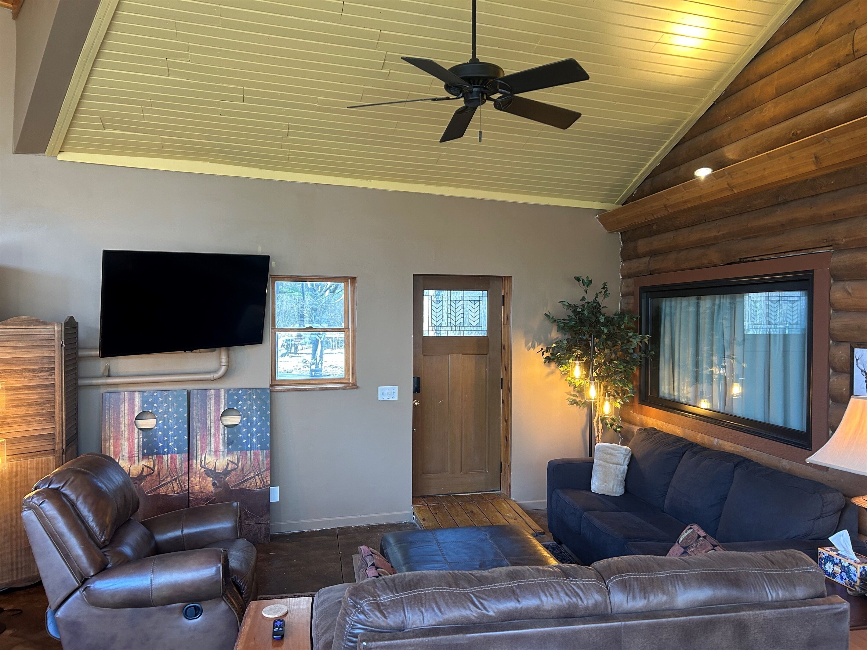 A living room with a ceiling fan, a television, a couch, and a fireplace.