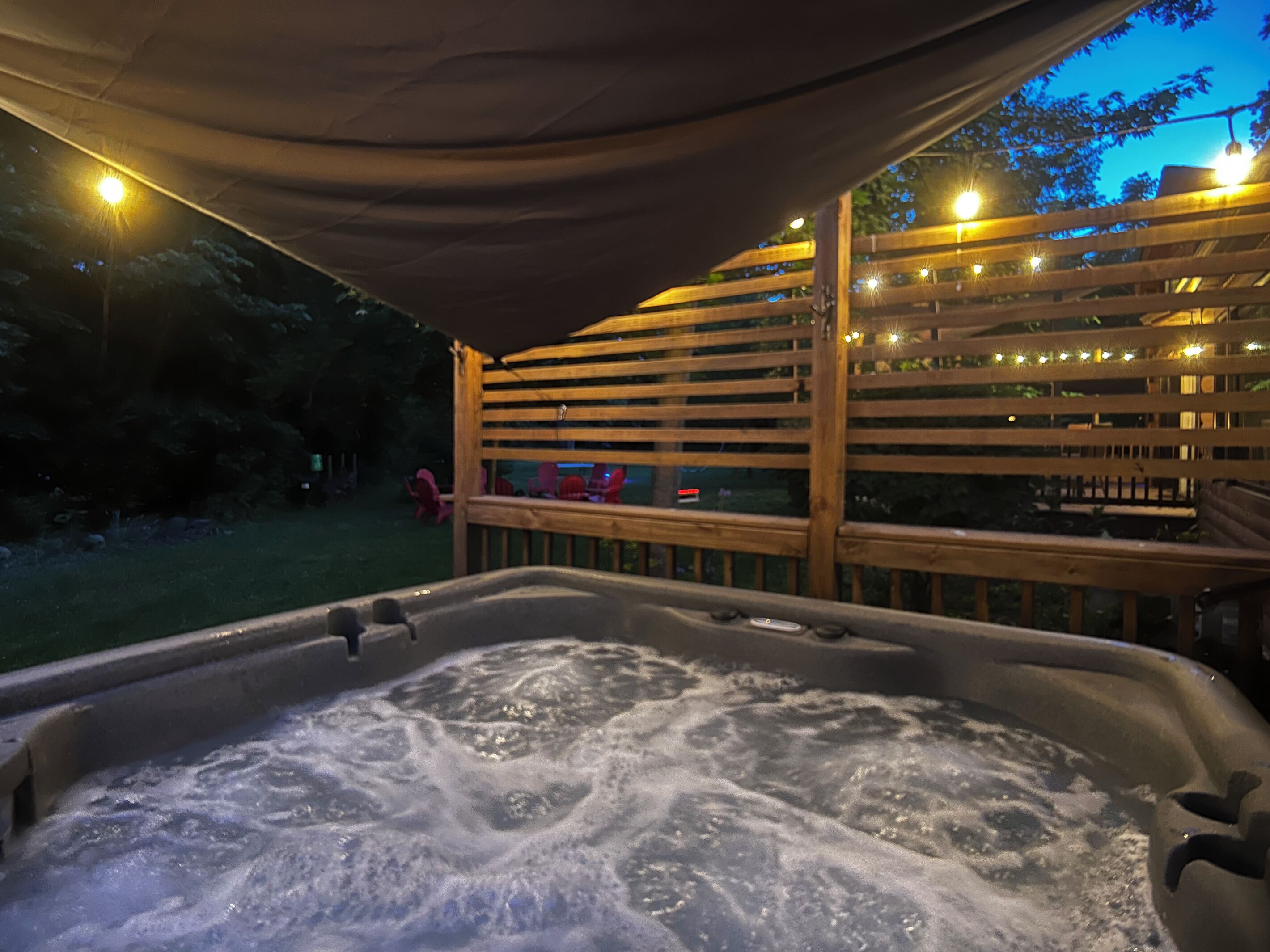 Un jacuzzi con terraza de madera y luces cálidas.